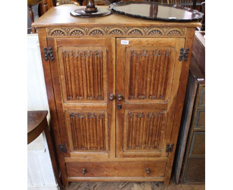 A carved light oak linen fold two door child's wardrobe