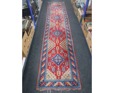 An Eastern carpet runner on red ground, 357cm by 76cm