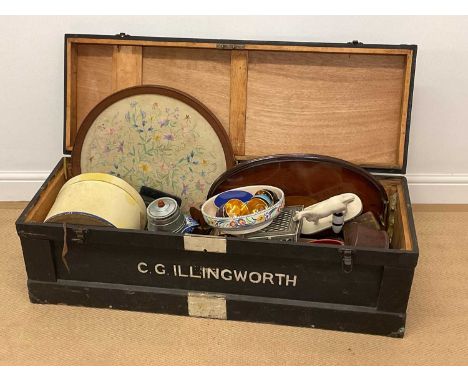 A wooden trunk with assorted contents comprising trays, ceramics, glass, metalware and a wooden lamp.