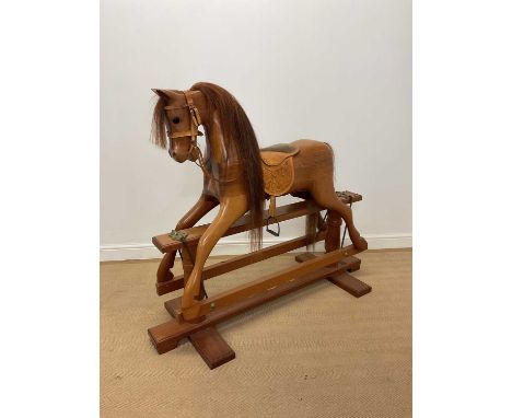 G. N. MAYES; a carved wooden trestle based rocking horse, with embossed leather detail to the saddle, length 140cm.Horse heig