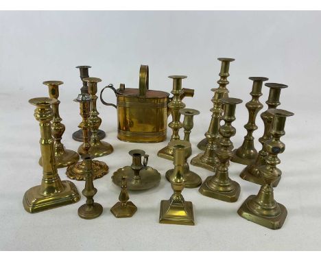 A collection of brass candlesticks, a chamber stick and a brass water can