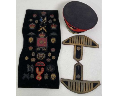 A mounted display of gold and silver thread military badges, a pair of shoulder epaulettes and a peaked cap.