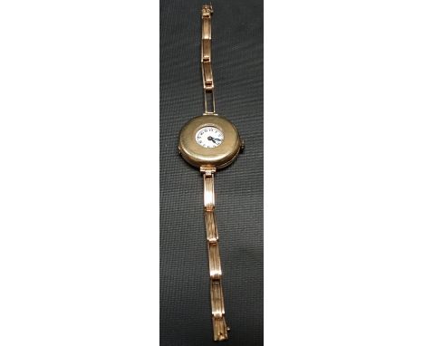 A 1920's 18ct gold cased half hunter ladies manual wind wristwatch, the 21mm white enamel dial with arabic numerals, the case