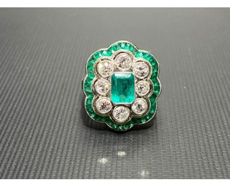 A good Art Deco style platinum, diamond and emerald cluster ring, the central emerald of 0.50ct spread approx, the nine diamo