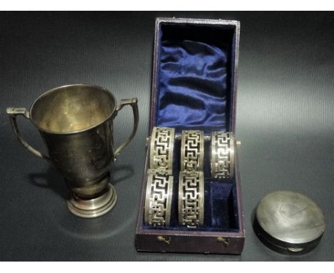 A silver hallmarked twin handled trophy cup together with a silver engine turned compact and a cased set of five silver napki