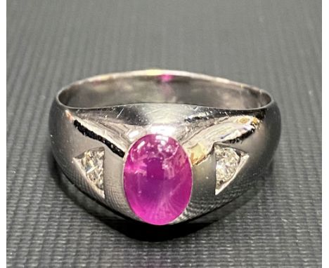 A modern 14ct white gold diamond and ruby set gents ring, the oval ruby cabochon of 1ct spread approx, flanked by two diamond