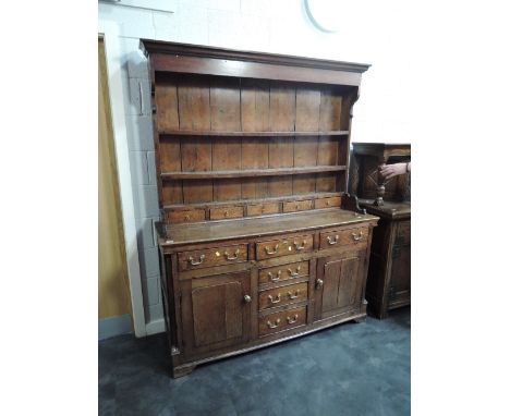 An 18th and later oak dresser having drawer Delft rack over frieze and central drawers flanked by cupboards, on bracket feet 