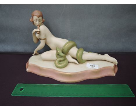 A Royal Dux figure modelled as naked flute playing maiden entwined with snake, signed Schoff