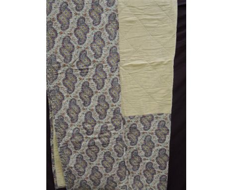 A vintage quilted bed cover of paisley design in shades of lemon, blue green & red with a lemon centre and lining