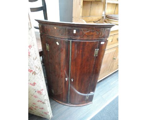 An early 19th century George III mahogany bow front corner cupboard having inlay decoration