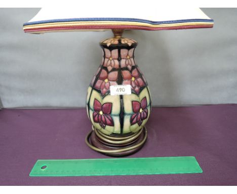 A modern Moorcroft table lamp in stylised floral pattern on green/puce ground, with shade