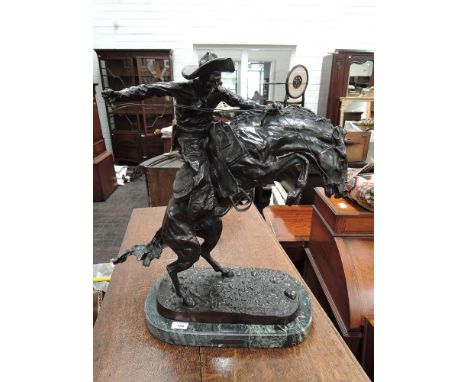 A bronze figure after Remington, modelled as cowboy on bucking bronco bearing signature, on marble plinth