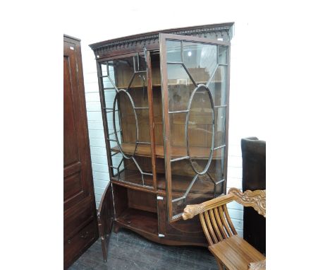 An Edwardian mahogany display cabinet having bow glass top over double cupboard with oval inlay decoration and splay feet