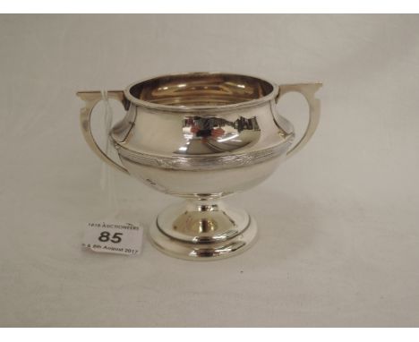 A small silver trophy having reed and cross decoration and architectural design handles, Birmingham 1935, James Fenton & Co