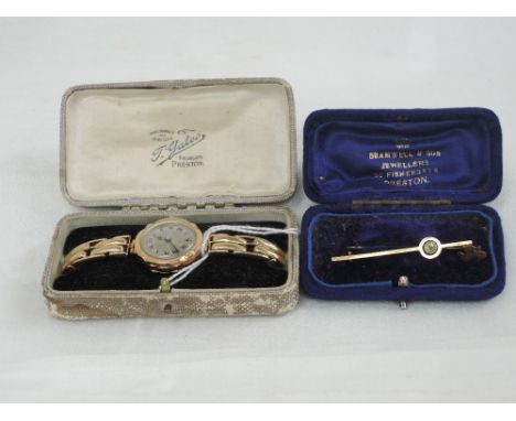 A lady's vintage 9ct gold wrist watch having Roman numeral dial to engine turned face in a shaped case on a yellow metal stre