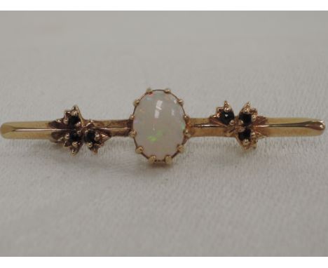 A yellow metal bar brooch having central opal with sapphire foliate decoration, no marks tested as 9ct gold