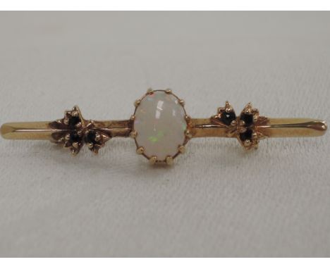 A yellow metal bar brooch having central opal with sapphire foliate decoration, no marks tested as 9ct gold