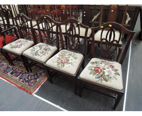A set of four early 19th century mahogany dining chairs having shield scroll backs, with later tapestry seats on square taper