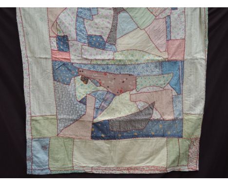 A vintage patchwork quilted single bed cover of multi coloured abstract design with red feather stitch decoration