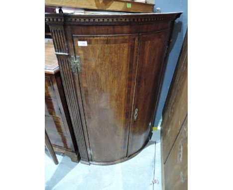 An early 19th century George III mahogany bow front corner cupboard having crossband decoration
