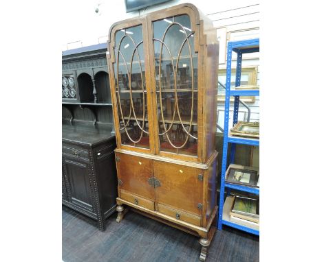 An early/mid 20th century golden oak bookcase of demi Art Deco design having arch step top and scroll glass panels over cupbo