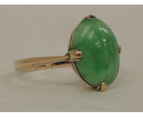 A lady's dress ring having an oval jade stone in a claw and collared mount on a yellow metal loop stamped 9ct,  approx 3.3g &