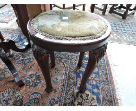 A 19th century mahogany stool in the Regency style having oval tapestry top on acanthus top, and semi cabriole legs