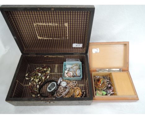 A vintage box containing a selection of costume jewellery including brooches, earrings, watches, beads etc