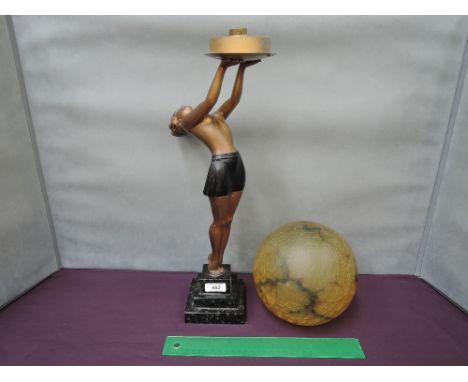 An Art Deco spelter table lamp modelled as topless lady holding aloft crackle glass globe, on stepped black marble base