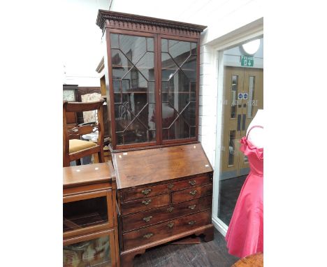 An early 19th century mahogany full height bureau bookcase having astral glazed top over fall front and drawer base on ogee b