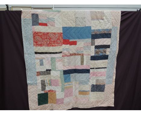 A vintage double sided patchwork quilted bed cover of multi coloured abstract design