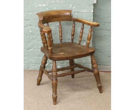 A hardwood smokers bow armchair with turned spindles.
