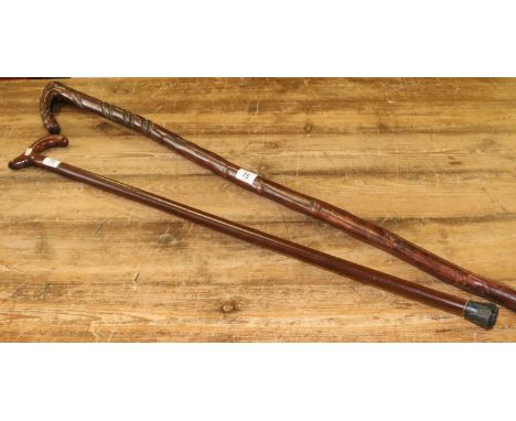 A carved walking stick decorated with a snake inset with a 1948 half crown coin along with another walking stick.