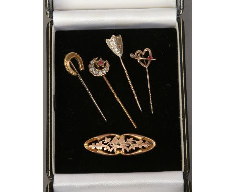 Four gold stick pins including two gem set and a pierced 9ct gold sweetheart brooch.