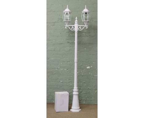A white painted garden light in the form of a Victorian two branch street light.