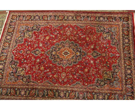 A red ground Persian Mashad carpet with traditional medallion design, 335 x 235cm.