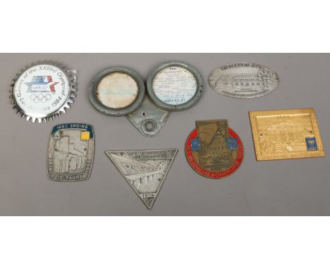 A collection of seven vintage automobile badges.