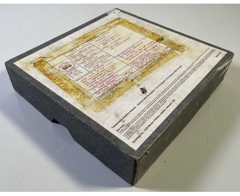 A boxed tape reel with handwritten label affixed by tape to the box suggesting contents are Frank Zappa recordings used for a