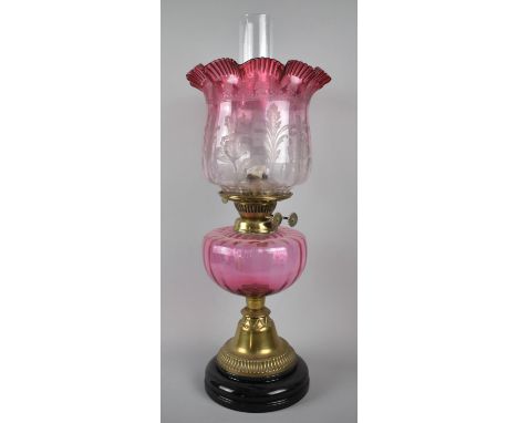A Late 19th Century Brass Based Oil Lamp with Cranberry Glass Reservoir and Etched Cranberry Wavy Rim Shade, 55cm high 