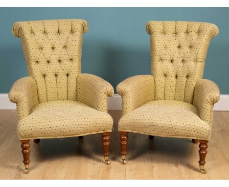 A pair of contemporary armchairs with button upholstered back, scrolling arms and turned front legs terminating in brass cast