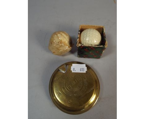 A Circular Brass Golf Ball Sponge together with Two Vintage Golf Balls