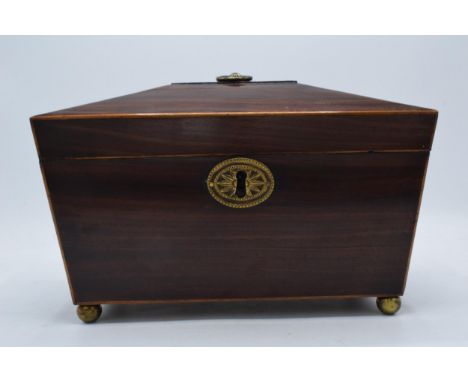 19th century wooden tea caddy of sarcophagus form with brass ball feet and brass handle. 28cm widest, 18cm tall.  In good con