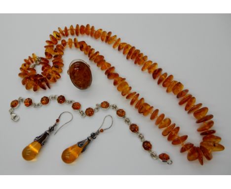 A string of amber pebble beads, a silver ring, bracelet and earrings all set with clarified amber with spangles Condition Rep