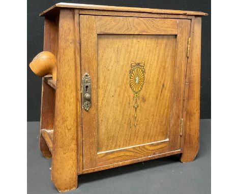 An Edwardian oak tobacco cabinet, transfer printed with batwing patera, fitted with drawers and shelves, 34cm high, 35cm wide