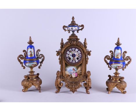 A cast clock set with enamel dial with address: "J.B. Burgers / Amsterdam" Underneath a porcelain plaque with pastoral repres