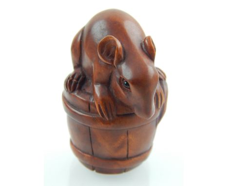 A carved wooden netsuke, fashioned with a rat on a barrel. 