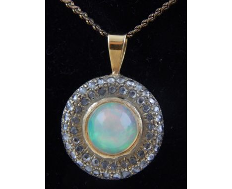 A yellow metal pendant with central collet set opal within a twin border of old cut diamonds on a fine link chain.