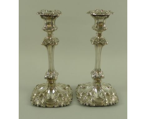 A pair of George IV silver candlesticks, Rococo style embossed with foliate decoration, with loaded bases, engraved with the 