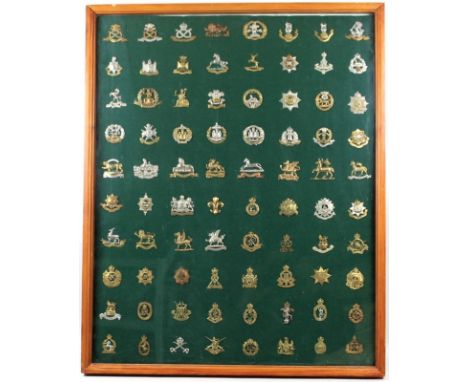 A collection of cap badges, arranged in a framed display case, to include British regimental cap badges, metal and staybright