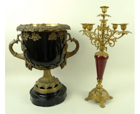 A black glazed ceramic urn with brass mounts, the rim cast with trailing vines and bunches of grapes, 32 by 24 by 38cm high, 